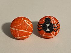 two orange buttons with black and white spider webs on them, sitting side by side