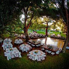 tables and chairs are set up for an outdoor wedding reception by the water at sunset