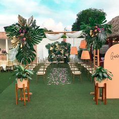 an outdoor wedding setup with chairs and flowers on the aisle, decorated with greenery