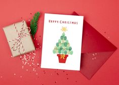 a card with a christmas tree on it next to a present box and pine branch