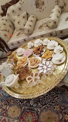 a table topped with lots of food on top of a gold tray next to a couch