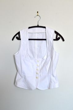 White cotton vest with mother-of-pearl buttons. Features a slightly tapered cut with structured panels at the front. Hits at the waist. Brand: Not listed Composition: Exterior: 96% cotton, 4% spandex; lining: 100% polyester Size: S Vintage Magic, Cotton Vest, Pearl Buttons, Mother Of Pearl Buttons, Vintage Vibes, Womens Clothing Tops, White Cotton, Sustainable Fashion, Mother Of Pearl