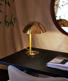 a table with a lamp on it next to a mirror and a chair in the background