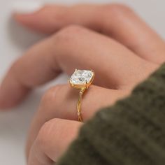 a close up of a person's hand holding a ring with a diamond on it