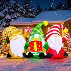 three inflatable christmas decorations sitting on top of a snow covered ground next to a house