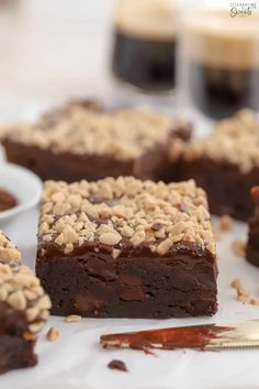 some brownies are on a white plate and one is cut into squares with chocolate toppings