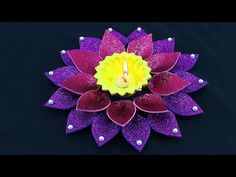 a candle that is sitting in the middle of a purple and yellow flower with pearls on it