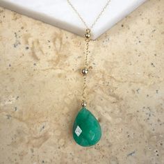 14KT yellow gold Y-necklace with emerald drop lariat. An eye-catching green emerald necklace in a flattering lariat style. Looks great worn alone or even stacked with other necklaces! 10.00 CT TW checkerboard-cut Emerald Dark Green Pear-Shaped Emerald Color Length: 18" Drop Length: 2" 14k Yellow Gold, Light Rope Chain Chain width: .85mm Spring ring clasp Polished gold bead spacers Green Emerald Necklace, Saint Jewelry, Emerald Color, Emerald Necklace, Gold Light, Fabric Ribbon, Large Crystals, Green Emerald, Lariat Necklace