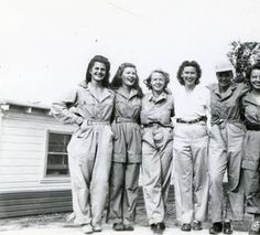 a group of women standing next to each other in front of a house