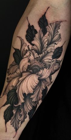 a black and white flower tattoo on the right arm, with leaves around it's center