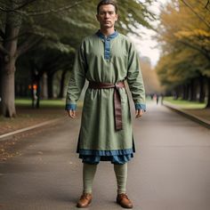 a man dressed in green and blue standing on the side of a tree lined road