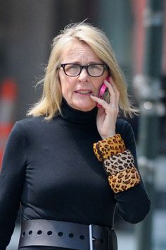 a woman talking on a cell phone while wearing a leopard print belt and black top