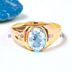 a gold ring with an oval blue topazte in the center and two smaller rocks behind it