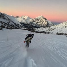 a person riding skis down a snow covered slope in front of some snowy mountains