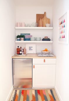 a small kitchen with white shelves and colorful rug