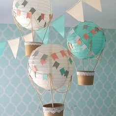 three paper hot air balloons are hanging from the ceiling in a room with blue and white wallpaper