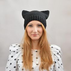 a woman with long red hair wearing a black knit cat ear hat on top of her head