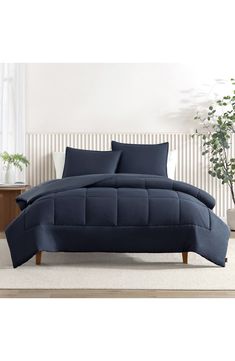 an image of a bed with blue comforter and pillows on the bottom half, in front of a white wall