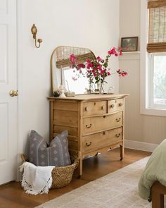 a bedroom with a dresser, mirror and flowers