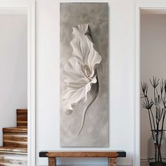 a large white flower sitting on top of a wall next to a wooden table and stairs