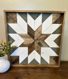 a wooden frame with white and brown designs on it next to a potted plant