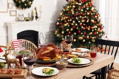 a dining room table set for christmas dinner with turkey and wine glasses on the table