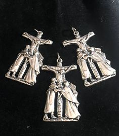 three silver colored metal crucifixs on a black surface with the image of jesus and mary