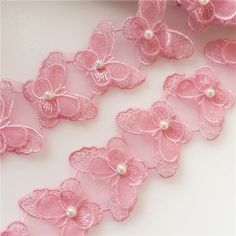 some pink flowers and pearls on a white surface