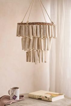 a wooden chandelier hanging from the ceiling next to a book and coffee cup