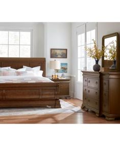 a bedroom scene with focus on the bed, dresser and mirror in the foreground