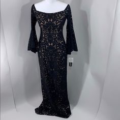 a mannequin wearing a black dress with long sleeves and an open neckline