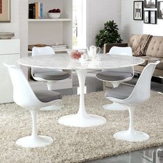 a white table with four chairs around it in a living room area next to a couch