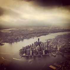 an aerial view of a large city in the middle of a body of water with dark clouds above it