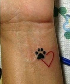 a dog paw and heart tattoo on the wrist