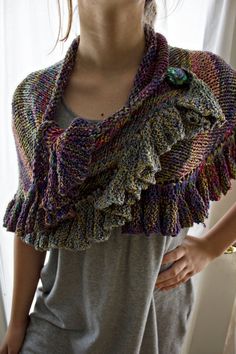 a woman standing in front of a window wearing a knitted shawl