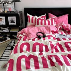 a bed with pink and white comforters on top of it next to a black headboard