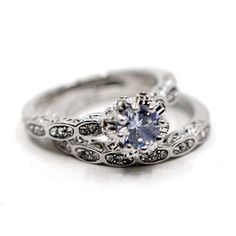 an engagement ring and wedding band set with a blue diamond in the center on a white background