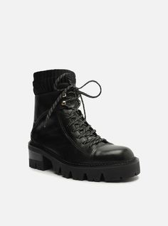 Black leather combat boot. The style features a mid-shaft, a rounded toe and a low rubber heel with a rugged, chunky lug sole with a stacked detailing. It has a snug-fitting vamp, lace closure in the color of the boot and a pull-tab on the back, making it easy to put on. The upper part of the shaft is made of knit material. Why follow this trend?These combat boots are essential items for the season! They feature a chunky lug sole in a super versatile tone and are a guarantee of comfort and style Black Leather Combat Boots, Genuine Leather Boots, Combat Boot, Rubber Heels, Lug Sole, Knitting Materials, Lace Closure, Leather And Lace, Tractor