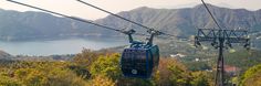 a cable car going up the side of a mountain with a lake in the background