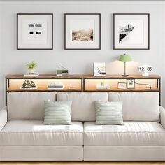 a living room with white couches and three framed pictures on the wall above them