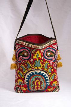 "Large Rectangular Flat Zipper Top Silk Petit Point Handbag created and handmade in Uzbekistan. Lined with silk ikat fabric, hand woven silk straps and tassels and a magnetic snap closure. Each handbag is hand drawn onto cotton canvas, inspired by original designs from Uzbekistan textile history.  11.5\" high x 9.5\" width, top opening 9\" wide,  approx. 54\" strap x 3/4\" width.  Can fit largest sizes of iPhone and Android. 100% silk petit point with handwoven silk ikat lining. Your purchase pr Artisan Red Embroidered Bag, Traditional Rectangular Shoulder Bag With Motifs, Red Rectangular Bags With Motifs, Multicolor Embroidered Rectangular Shoulder Bag, Bohemian Bags With Multicolor Intricate Embroidery, Rectangular Shoulder Bag With Multicolor Embroidery, Traditional Shoulder Bag For Travel, Traditional Red Bags With Motifs, Traditional Rectangular Shoulder Bag With Intricate Embroidery