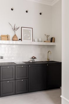 a kitchen with black cabinets and white walls