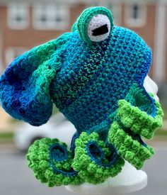 a crocheted blue and green hat on top of a white mannequin