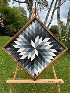 a black and white quilt sitting on top of a wooden easel in the grass