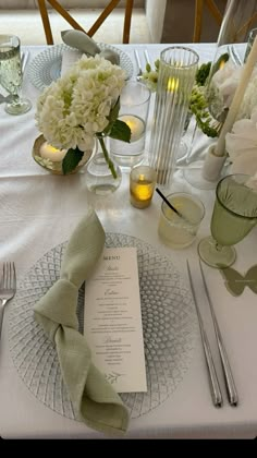 the table is set with white flowers and silverware