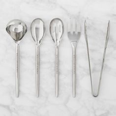 five silver spoons and two forks on a marble surface