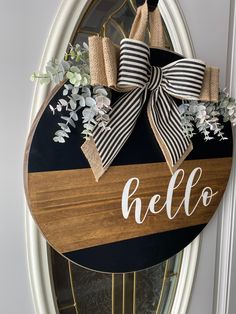 a wooden sign that says hello to the front door with flowers and ribbon on it