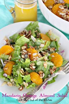 a salad with oranges, almonds and lettuce on a white plate