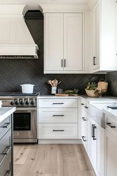 a kitchen with white cabinets and black backsplash