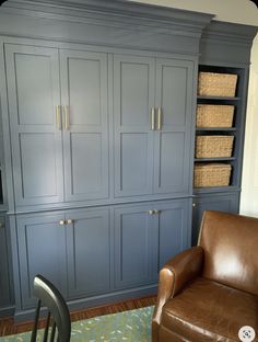 a brown leather chair sitting in front of a blue cabinet